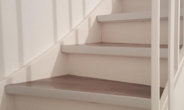 Lackierte Holztreppe innen Teilansicht einer gewendelten Holztreppe mit weißen Wangen und dunklen Stufen.