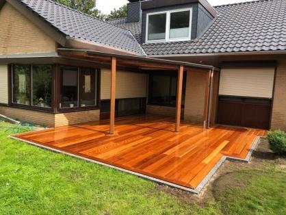 Großzügige Holzterrasse aus glänzend versiegeltem Hartholz mit Überdachung an einem Einfamilienhaus, professionell verlegt im Außenbereich.