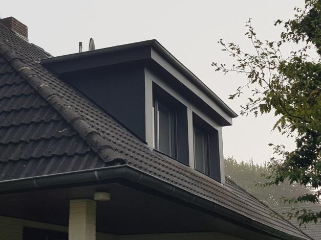 Modernes Dachfenster an einem nebeligen Morgen Dachfenster an einem Haus mit schiefergrauem Dach und dunkelgrauer Verkleidung an einem nebligen Morgen, umgeben von Bäumen.