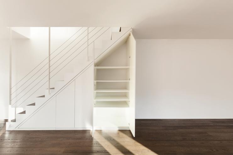 Nischenlösung für Einbauschrank unter Treppe Geräumiger Einbauschrank unter weißer Treppe mit Schubläden und Türen und offener Regalgestaltung an dunklem Parkett
