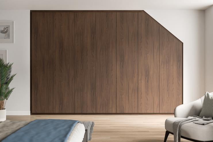 Maßgefertigter, dunkelbrauner Schrank, der sich harmonisch in die Schräge eines stilvollen Schlafzimmers einfügt.