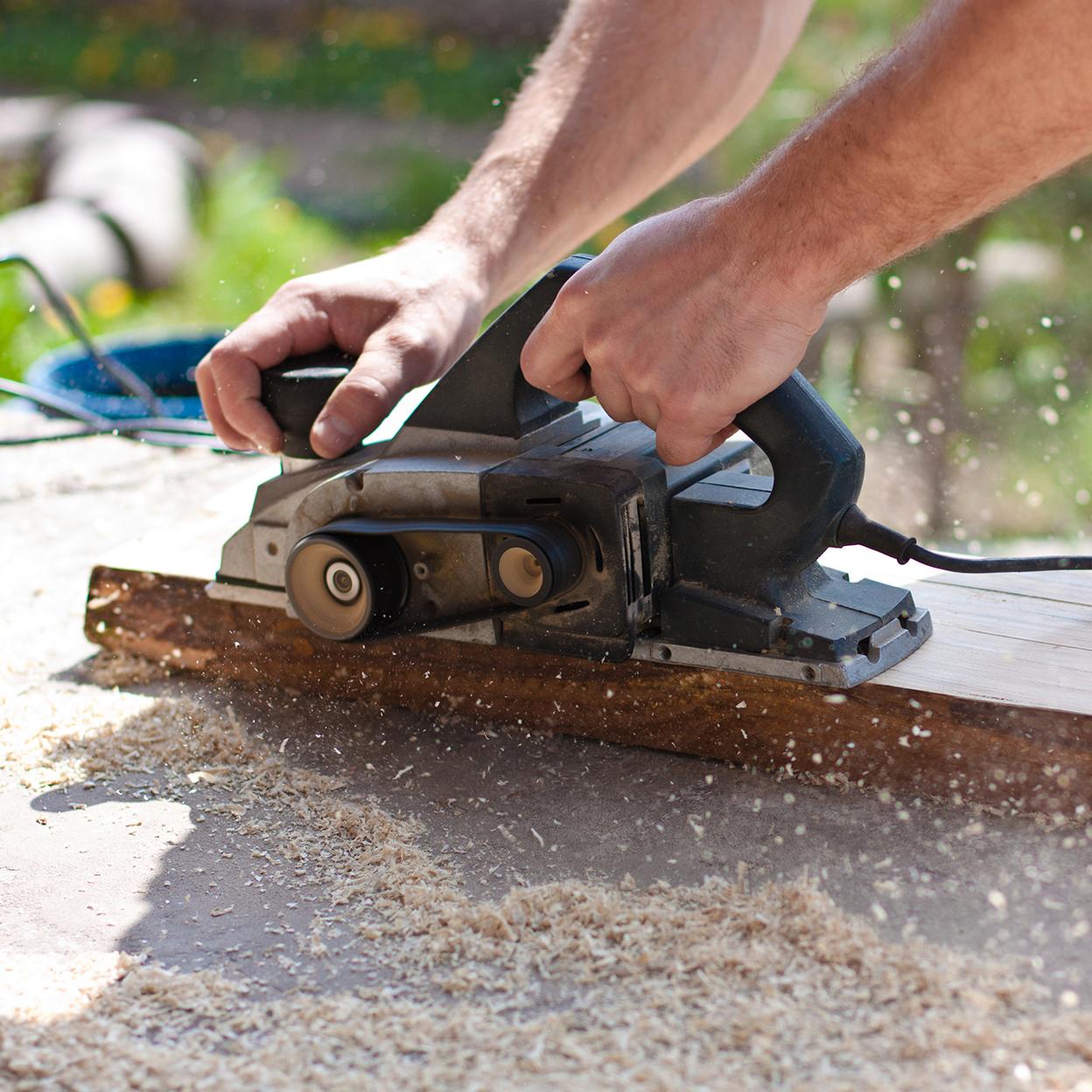 Mann mit Elektrohobel - Hobelspäne - Querformat